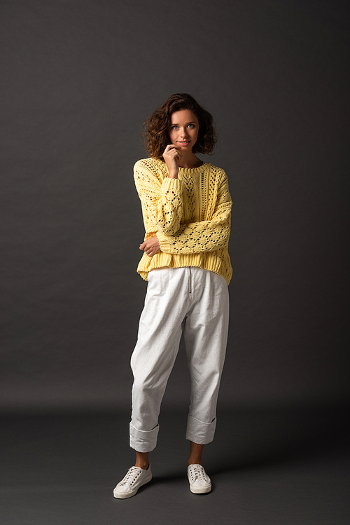 curly woman in yellow sweater on black background