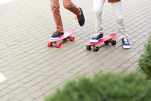 cropped view of two boys riding penny boards on pavement