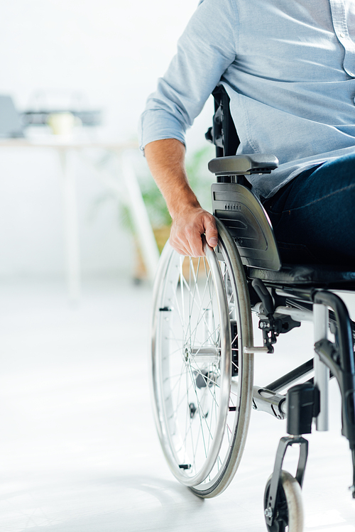 partial view of man sitting in wheelchair in living room