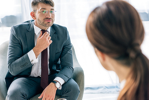 selective focus of handsome businessman in suit and glasses talking with journalist