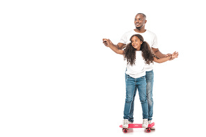 smiling african american father supporting adorable daughter skateboarding on white background