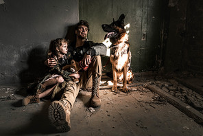 man and kid with teddy bear sitting on floor with german shepherd dog, post apocalyptic concept