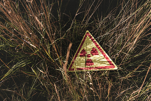 top view of triangle with warning toxic symbol on grass, post apocalyptic concept