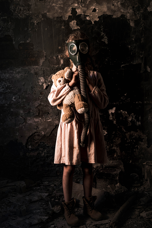kid in gas mask standing and holding teddy bear, post apocalyptic concept