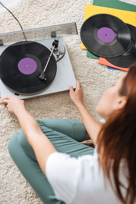 selective focus of vintage record player near girl sitting on carpet