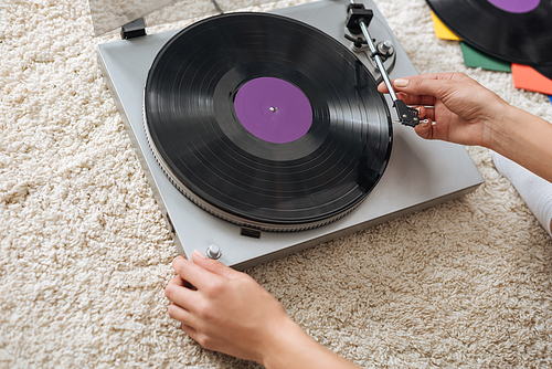 cropped view of young woman touching retro record player