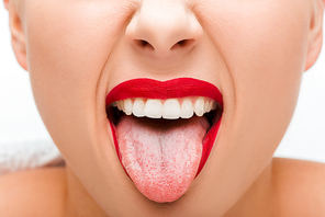 cropped view of young woman with red lipstick sticking out tongue isolated on white