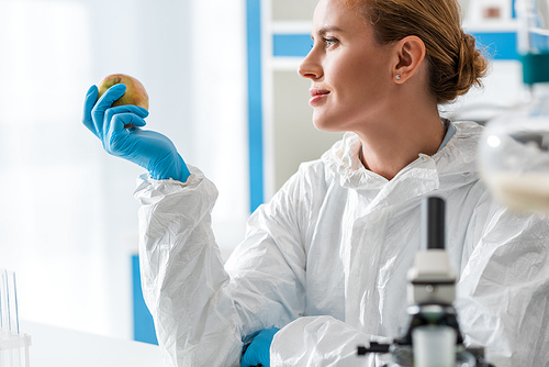 selective focus of biologist holding whole apple in lab