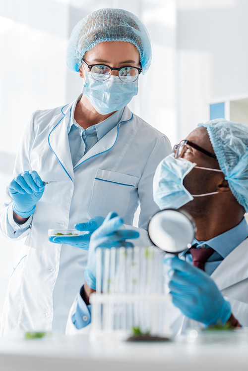 african american biologists talking with colleague and pointing with finger at test tubes