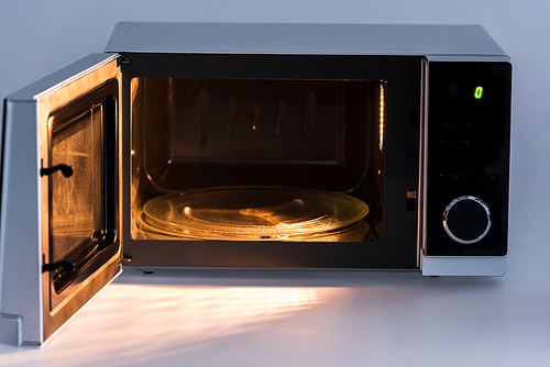 metal and opened microwave oven with light on white background
