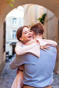 happy young woman embracing boyfriend on street with closed eyes