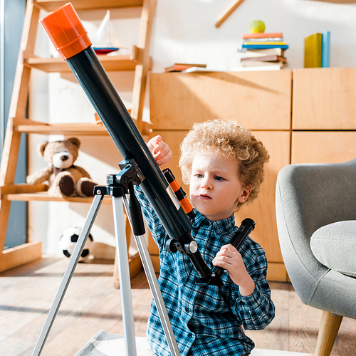 smart child touching telescope near armchair