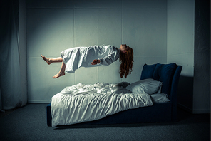demonic girl in nightgown levitating over bed