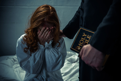 exorcist holding bible and hugging crying girl in bedroom