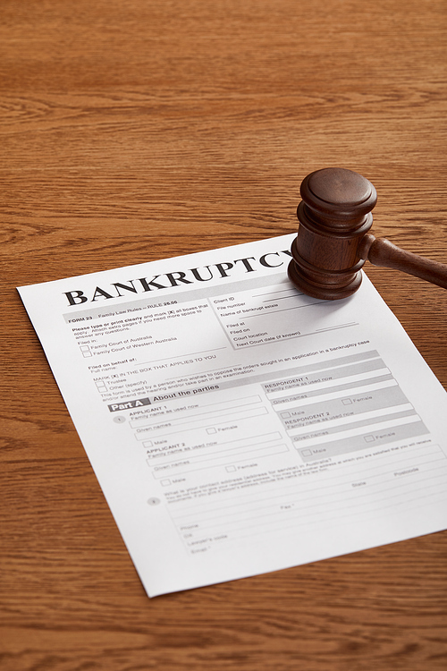 bankruptcy form with wooden gavel on brown wooden surface