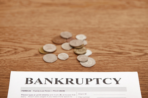 bankruptcy form and metal coins on brown wooden table