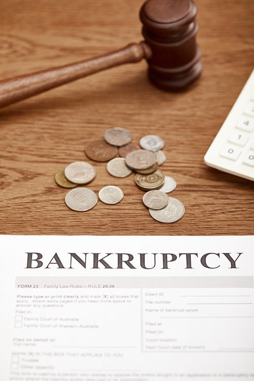 bankruptcy form, gavel and coins on brown wooden table