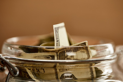 close up view of glass jar with dollar banknotes