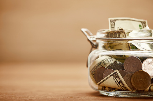 close up view of glass jar with dollar banknotes and metal coins