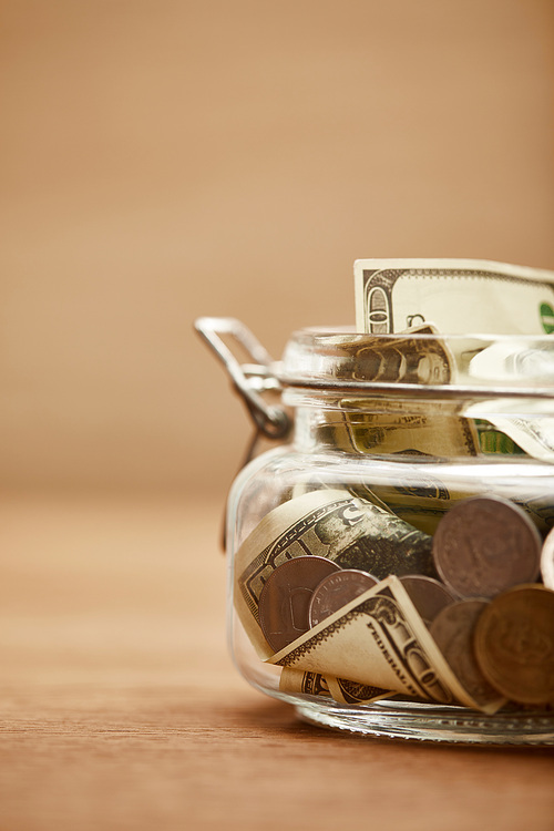 close up view of glass jar with dollar banknotes and coins