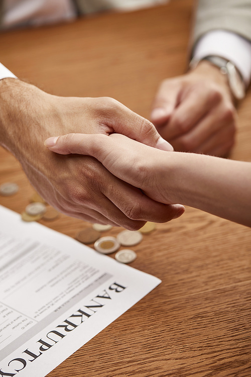 cropped view of man and woman shaking hands near bankruptcy form