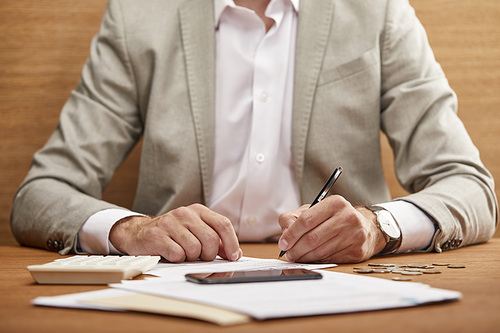 partial view of businessman in suit filling in bankruptcy form at wooden table