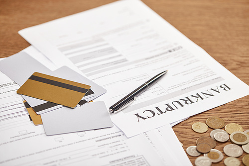 bankruptcy form among documents, credit cards and coins on wooden table