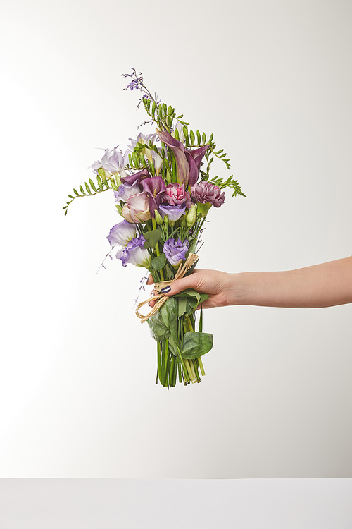 cropped view of woman holding bouquet of violet and purple flowers on white
