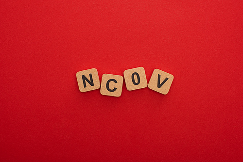 Top view of wooden blocks with ncov letters on red background