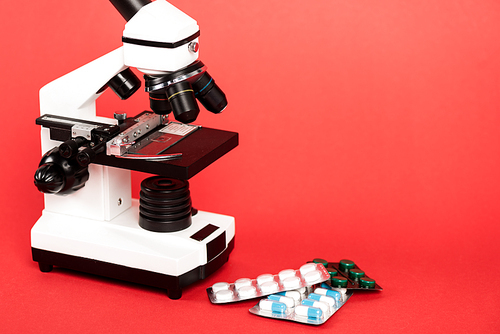 microscope near pills in blister packs on red
