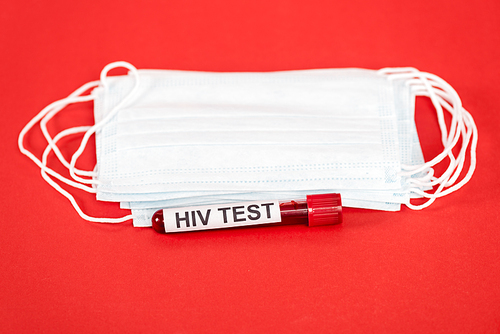 sample with hiv test lettering near protective medical masks isolated on red