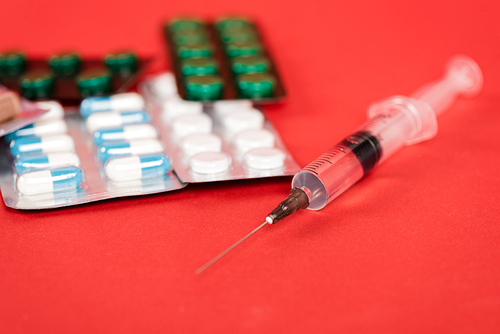 selective focus of syringe near pills on red