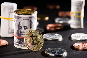 close-up view of rolled dollar banknotes and bitcoins on black