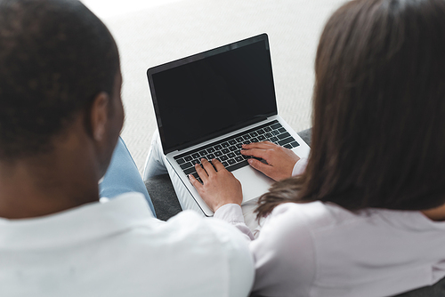 back view of african american couple looking at laptop at home