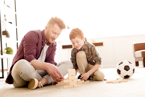 smiling father and son playing with wooden blocks at home