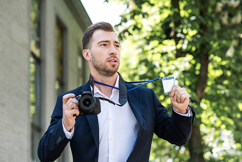 photojournalist in formal wear with digital photo camera and press pass