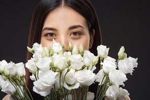 portrait of asian woman with beautiful dark hair and bouquet of white eustoma flowers isolated on black