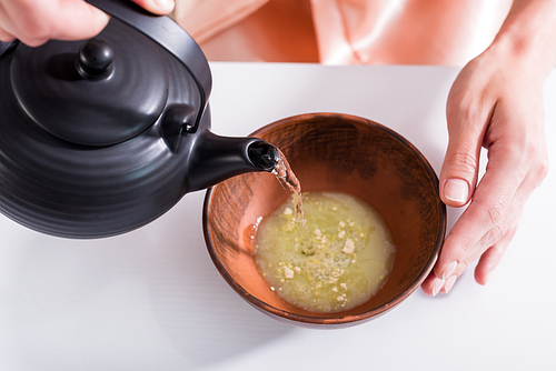 cropped shot of woman making tea while having tea ceremony in morning at home