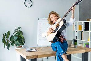 attractive businesswoman playing acoustic guitar in office