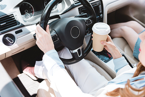 partial view of businesswoman with coffee to go driving car with daughter near by
