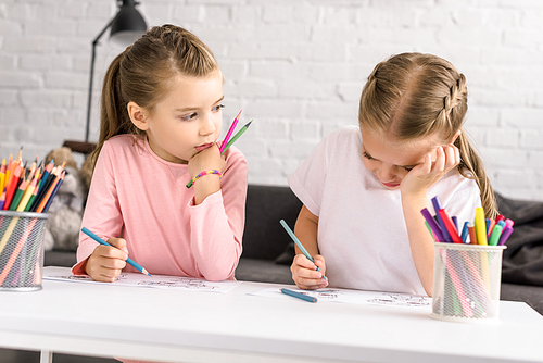 portrait of cute little kids drawing pictures at table at home