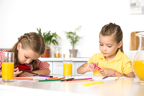 portrait of cute little kids drawing pictures at table at home