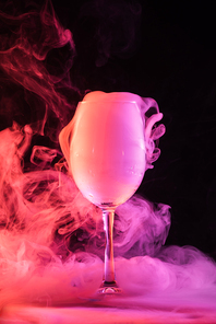 wine glass full of pink smoke on dark background