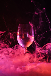 empty glass with pink smoky swirls around on black background