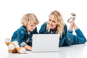 mother and son using laptop on floor on white