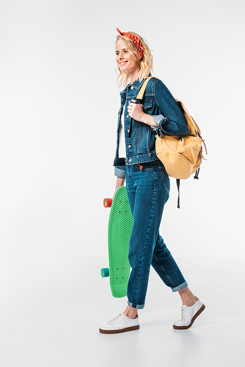 attractive woman walking with bag and skateboard isolated on white