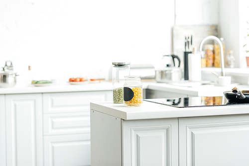 interior of empty modern white kitchen with jars on table