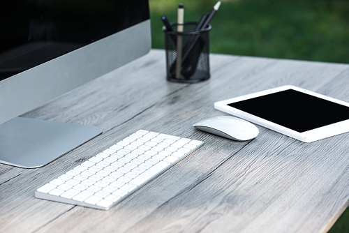 selective focus of digital tablet and computer with blank screens at table outdoors