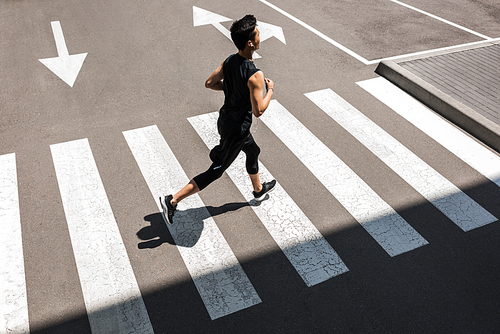 high angle view of young asian sportsman in earphones running at city street