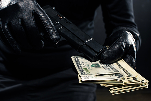 Close-up view of gun and dollars in hands of robber